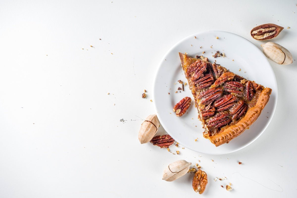 Pecan pie slice on a white plate with delicious pecan pie filling.